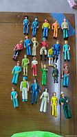 Top view of all 25 Fisher-Price action figures arranged on wood surface