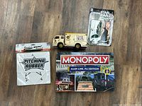 Group shot of all four items: Monopoly game, Han Solo figure, Borden’s truck, pitching rubber.