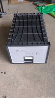 Front view of plastic file drawer showing black top, white front with label holder