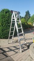 Full view of aluminum A-frame ladder standing on patio