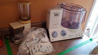Coffee grinder, food processor base with bowl and bagged discs on countertop