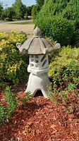 Full view of concrete pagoda statue in garden bed