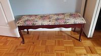 Full view of bench showing floral upholstered seat, cabriole legs, wood frame