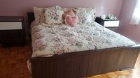 Overall view of dark wood king bed, split mattress, floral linens