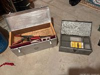 Large silver chest open showing interior wood rail and small galvanized parts box beside it closed