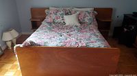 Full view of queen bed with floral linens and wooden footboard