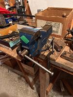 Full view of blue engineer’s bench vise mounted on workbench