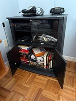 Overall view of media cabinet with items inside and on top