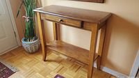 Front view of wooden hall table showing top, drawer, shelf and legs