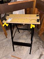 Overall view of folding workbench showing wood top, metal frame, clamp handles and stops