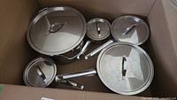 Top view of cookware with lids on showing 5 lidded pieces inside box