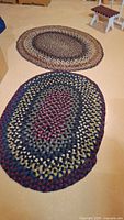 Two oval braided rugs laid out on floor
