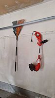 Overall view of rake and trimmer hanging on wall