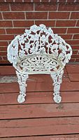Front view of white cast iron garden bench showing ornate backrest, seat, and legs