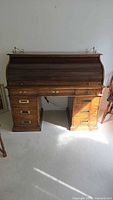 Full view of closed rolltop desk showing drawers and brass hardware