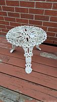 Full view of round white wrought iron side table on deck