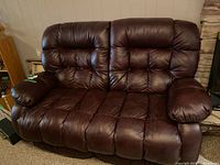 Front view of burgundy leather reclining loveseat showing tufted cushions and pillow arms