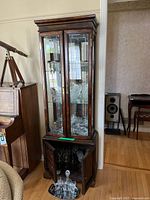 Full front view of tall dark-stained wood china cabinet showing etched glass doors, glass shelves, mirrored back, lower storage section