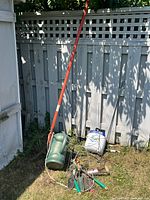Group of garden tools and supplies leaning against fence