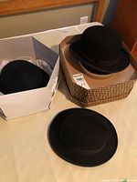 Three black hats displayed with two hat boxes