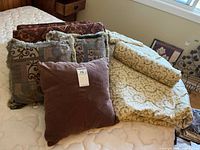 Group view of four pillows and rolled comforter on bed