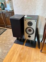 Pair of Paradigm 5se speakers on stands, one grille removed showing drivers