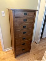 Full front view of tall chest showing all seven drawers and metal pulls