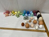 Group shot of all multicolor ceramic eggs, frog figures, pig shell with measuring rulers