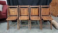 Four wooden folding chairs standing upright