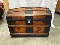 Front view of wooden trunk with black metal accents