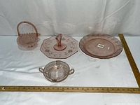 overview of all four pink pressed glass pieces with rulers for scale