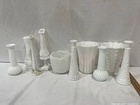 Eight assorted white milk glass vases lined up