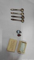 Lot overview showing four 835 silver spoons, two gemstone pendants, and Hans Schott box