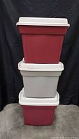 Stacked view of three totes showing two red and one gray with lids