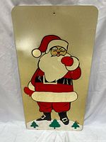 Front view of metal sign showing Santa graphic and wear