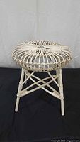 Front view of white wicker stool showing legs and seat design