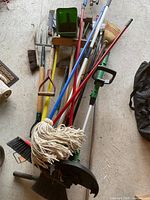Pile of assorted garden and cleaning tools on floor