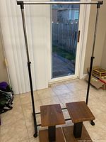 Full view of garment rack with two wood pedestal tables underneath