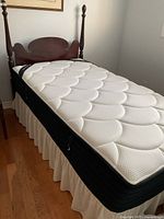 Full view of twin mattress on box spring with bed skirt and headboard