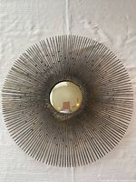 Full view of metal sunburst wall decor showing radial rods and central disk