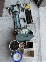 Mixed lot of garden watering accessories, rolling seat, tool tote, wire supports and assorted planters displayed on floor