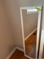 Full view of mirror leaning against wall showing size and frame