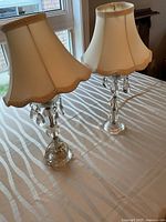 Pair of crystal table lamps with ivory shades on table