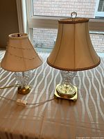 Both crystal and brass lamps with shades on tabletop