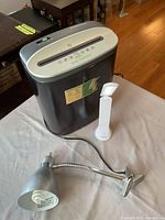 Paper shredder, silver clamp lamp, white LED lamp displayed on table