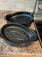Two nested black enamel roasting pans with white speckles, view of interiors