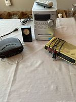 All items displayed: Sony stereo unit, remote, Sony Dream Machine, beige clock radio, black desk clock, cables