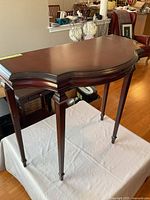 Front and side view of dark mahogany demilune console table on white surface