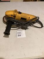 Full view of DeWalt DW400 angle grinder with side handle, disc, cord and lot tag visible