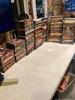 Wide shot of multiple tall stacks of DVD cases on folding table